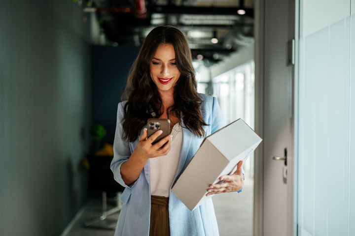 Žena pracuje s mobilnou aplikáciou a drží balík