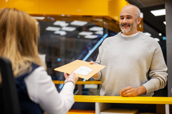 Zákazník odovzdáva balík zamestnankyni pri priehradke