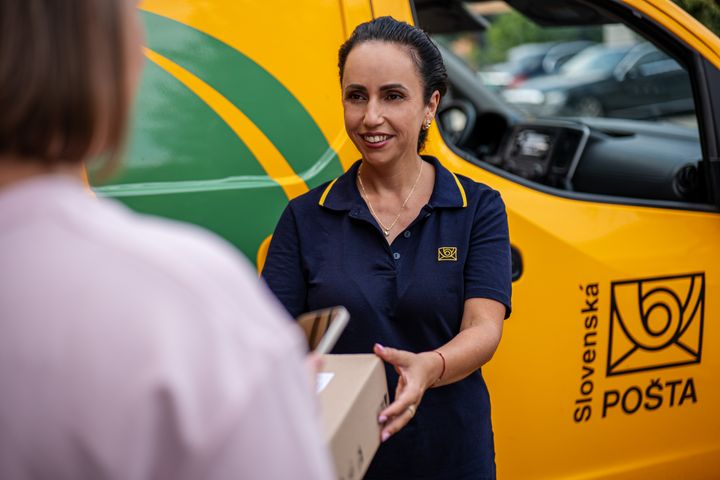 Poštárka odovzdáva zásielku pri aute
