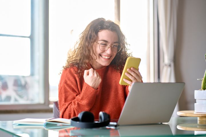 Nadšená žena s mobilom ukazuje gesto radosti
