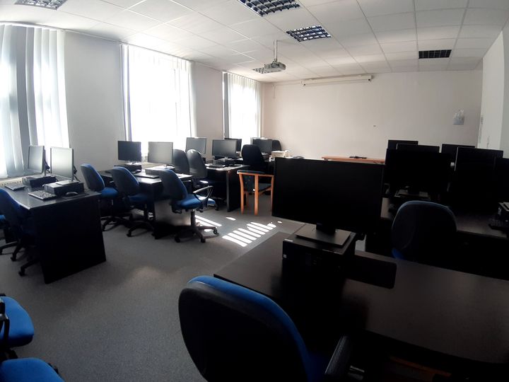 Učebňa so stolmi s počítačmi a monitormi pre približne 12 osôb